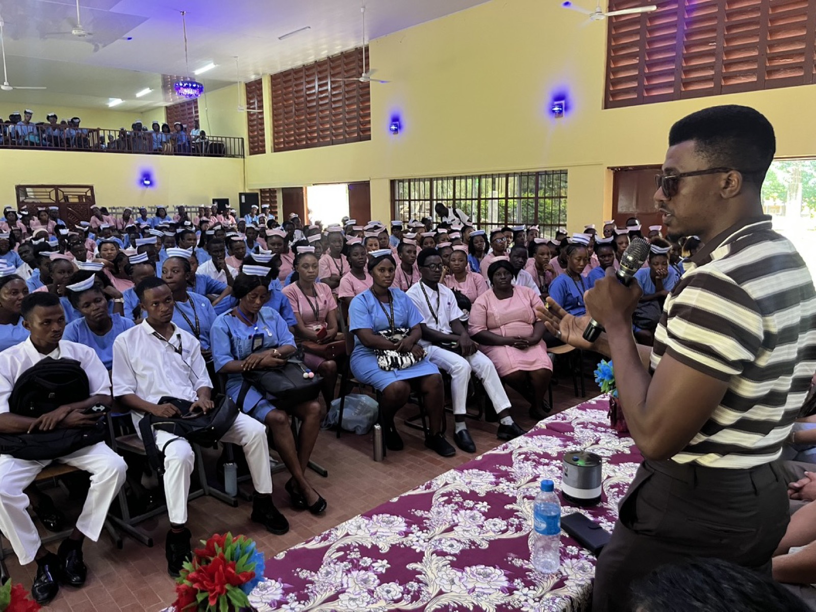 A speaker presenting the AISHA device to a full hall of nursing students