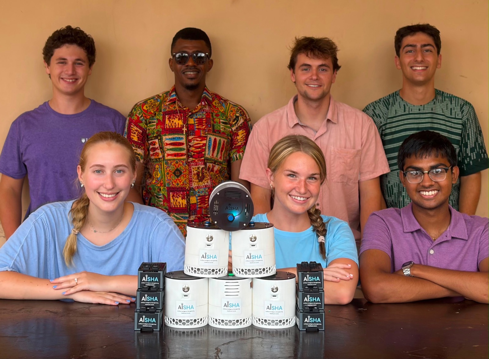 Seven AISHA team members holding assembled AISHA devices
